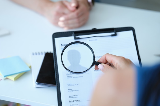 Photo l'employé examine le formulaire de demande de curriculum vitae à la loupe