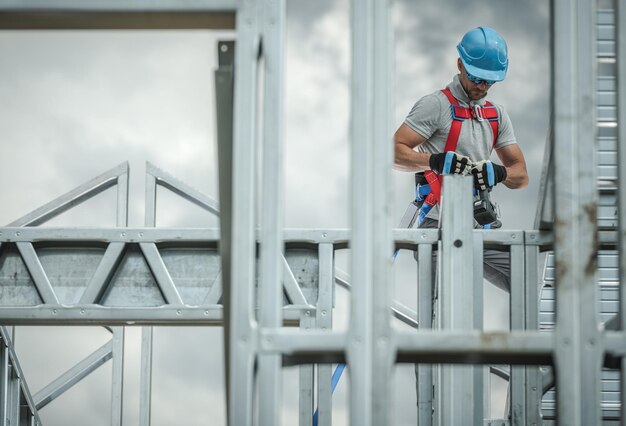 Photo employé de l'industrie de la construction, homme de race blanche, ouvrier du cadre squelettique, d'une trentaine d'années, harnais de sécurité