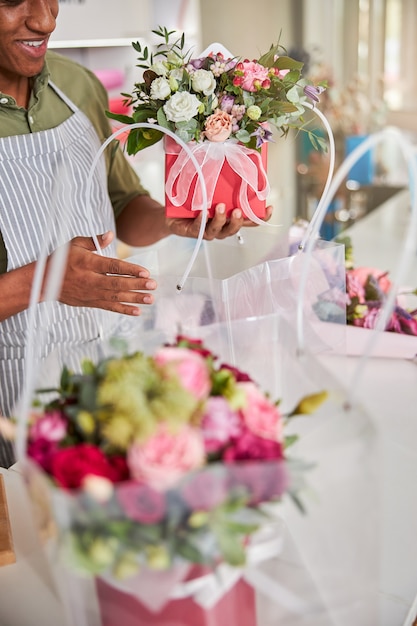 Employé de magasin de fleurs mettant un pot de roses dans un emballage en plastique