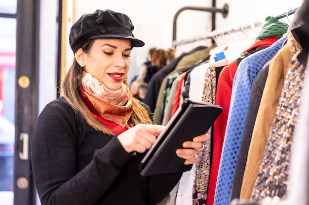 Employé de magasin de vêtements Latina passant une commande avec une tablette, un magasin de vêtements d'occasion et durables