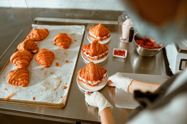 Photo l'employé met une assiette avec un délicieux croissant frais sur le comptoir d'une boulangerie artisanale