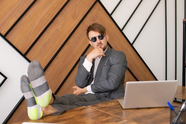 Un employé paresseux Assis devant un ordinateur portable Les pieds sur la table Un concept ennuyé au travail