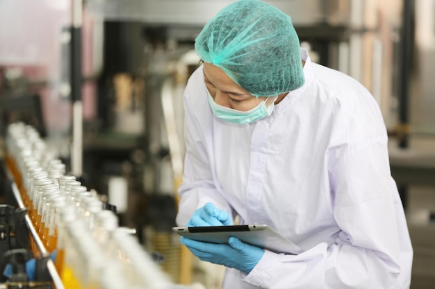 L'employé de la production de boissons travaille dans la chaîne de production de contrôle de la qualité de la fabrication d'aliments et de boissons