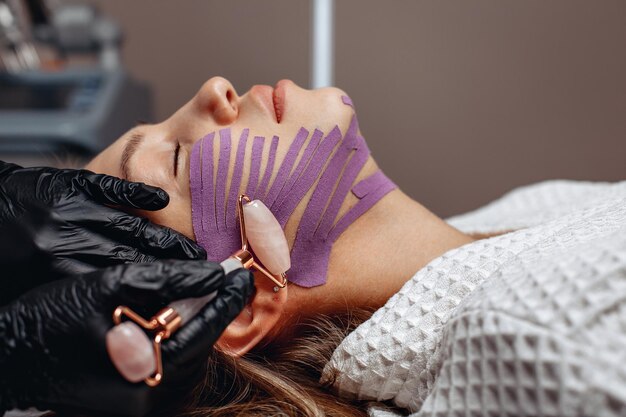 Un employé d'un salon de beauté effectue une procédure de soin de la peau en les lissant avec un masseur à quartz