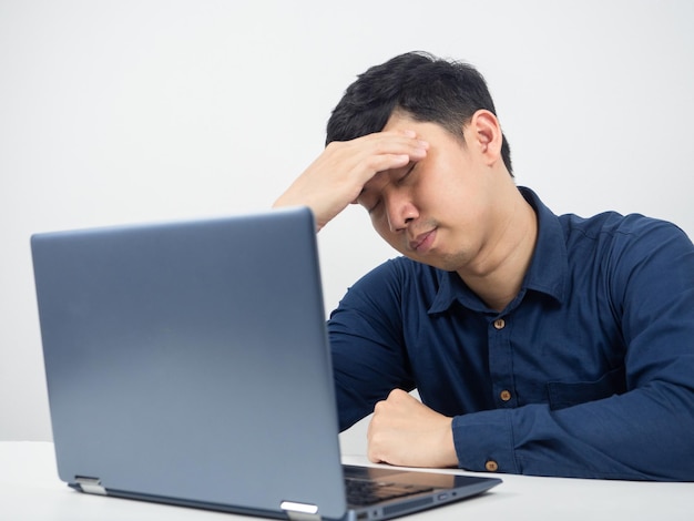 Employé de sexe masculin assis avec un ordinateur portable se sentant éprouvé et mal à la tête au travail