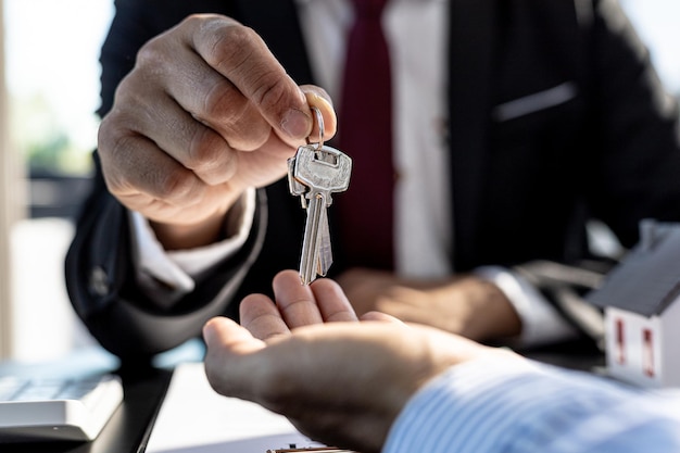 Un employé d'une société de location de maisons remet les clés de la maison à un client qui a accepté de signer un contrat de location, expliquant les détails et les conditions de la location. Idées de location de maisons et de biens immobiliers.