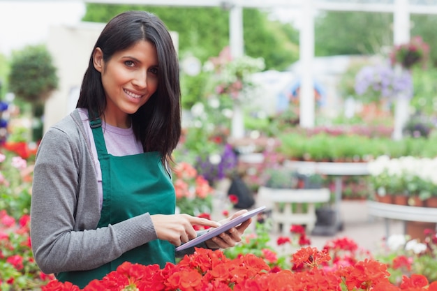 Employé souriant à l&#39;aide de tablet pc pour vérifier les fleurs