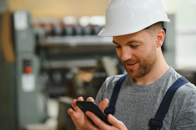 Employé souriant et heureux Ouvrier industriel à l'intérieur de l'usine Jeune technicien avec un casque blanc