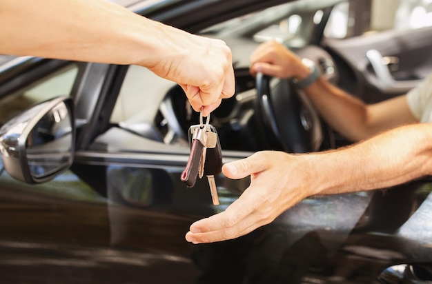 Un employé de stationnement donne la clé à un homme assis dans la voiture.