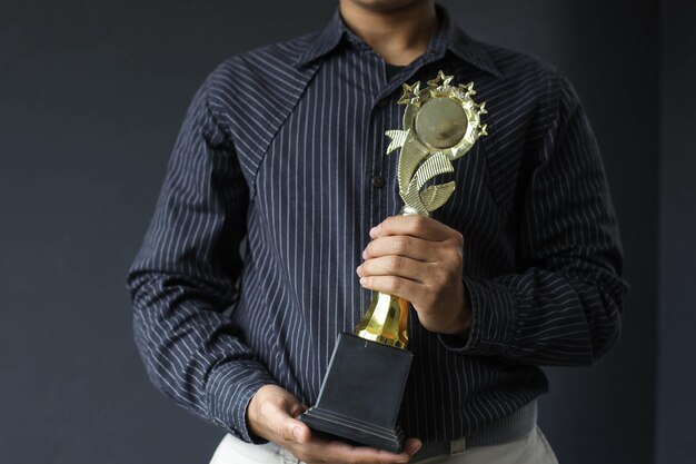 Employé tenant un trophée pour ses réalisations isolées sur fond gris