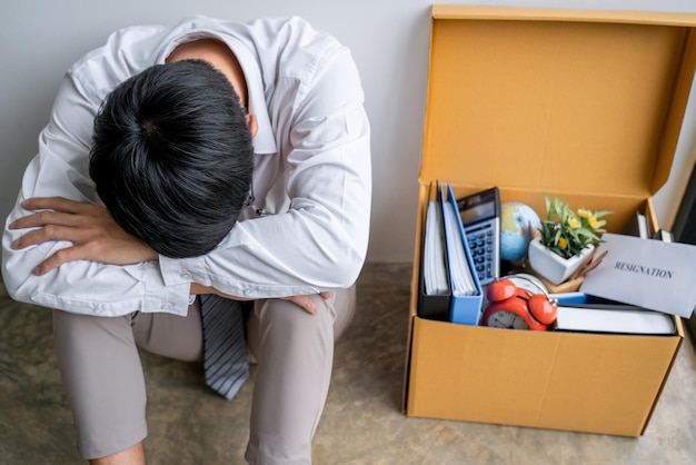 Un employé triste assis près d'une boîte en carton.