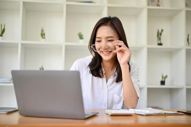 Employée de bureau asiatique attrayante portant des lunettes travaillant à son bureau