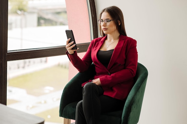 Employée de bureau assise et utilisant un téléphone portable au bureau pendant la journée de travail