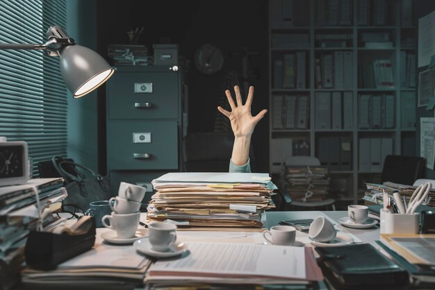 Photo une employée de bureau désespérée accablée de paperasse demande de l'aide avec sa main.