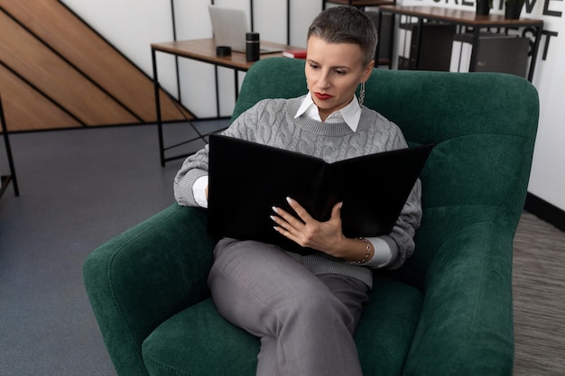 Employée de bureau femme avec un dossier pour les documents dans ses mains est assise sur une chaise