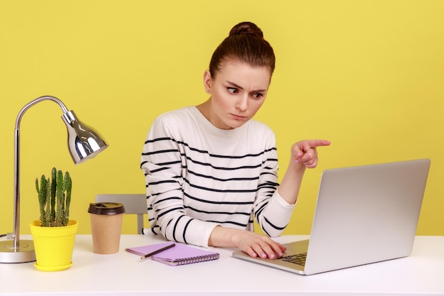 Une employée de bureau sérieuse assise sur le lieu de travail en train de gronder en disant que je vous l'ai dit