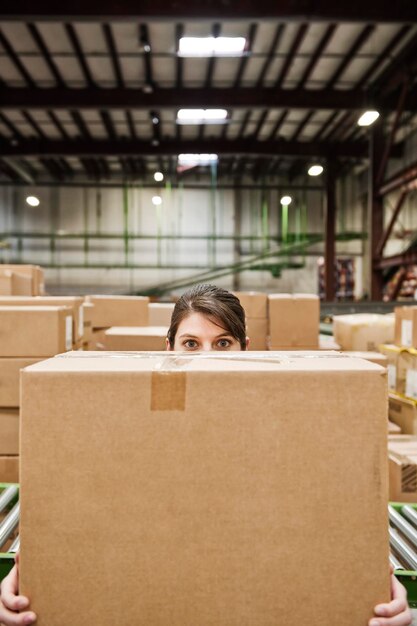 Photo une employée d'entrepôt caucasienne derrière une boîte en carton dans un entrepôt de distribution