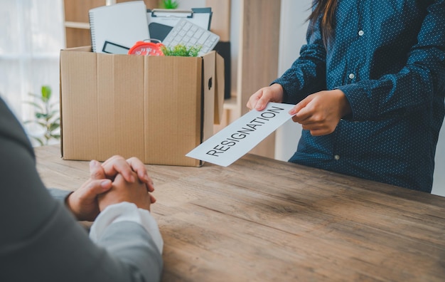 Photo une employée de l'entreprise remet une enveloppe blanche avec une lettre de démission à l'intérieur à son patron ou aux rh avant de quitter son lieu de travail