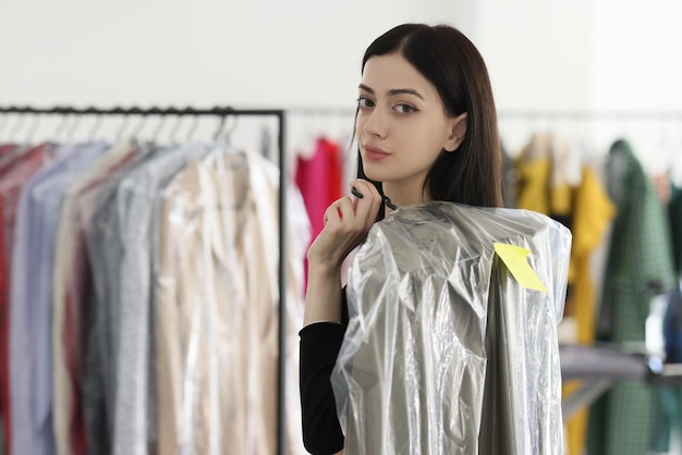 Une employée tient une chemise lavée dans un service de nettoyage à sec une femme brune prévoit de donner des vêtements