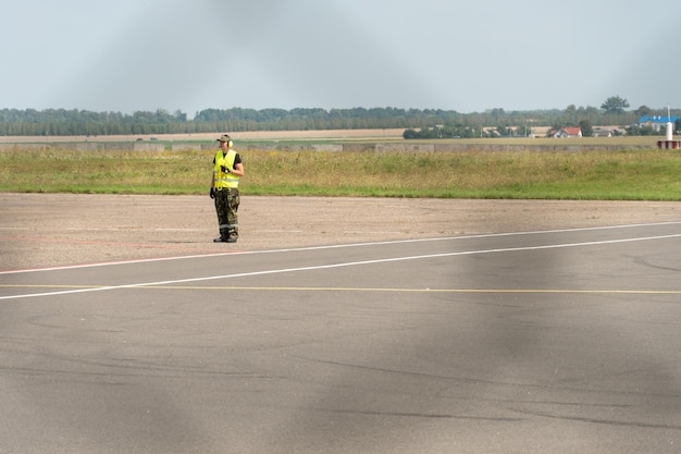 Les employés de l'aéroport sont sur la piste Le territoire de l'aérodrome privé est clôturé avec des barbelés et une clôture Le contrôleur de la circulation dirige l'avion