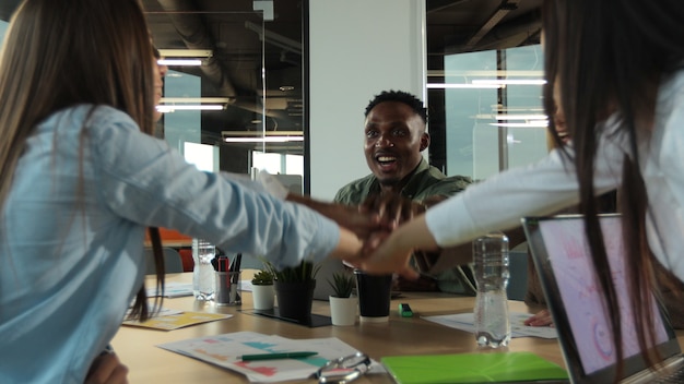 Photo employés de bureau faisant des exercices de consolidation d'équipe en empilant les mains dans l'esprit unificateur de la créativité et de la cause commune