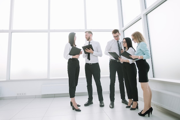 Les employés discutent de documents commerciaux debout dans le hall du bureau