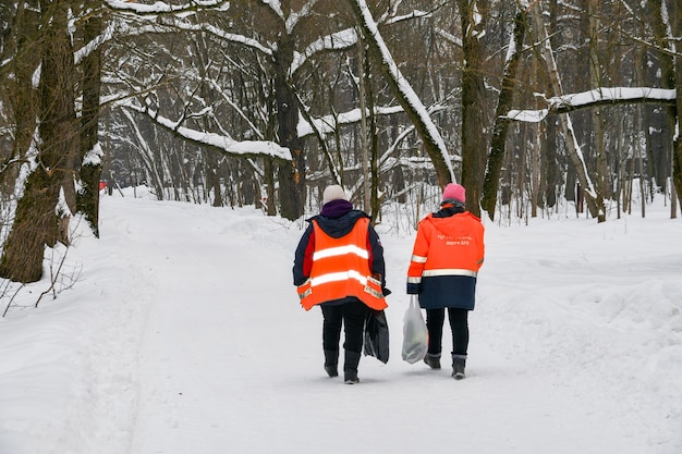 Les employés du parc de la ville en vestes orange marchent le long de l'allée 03 février 2022 Moscou Russie