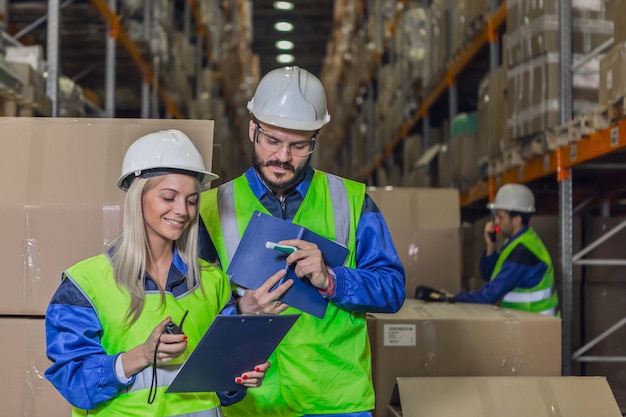 Employés d'entrepôt souriants en uniforme regardant des documents