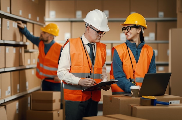 Des employés d'entrepôt vérifiant les commandes sur l'ordinateur portable