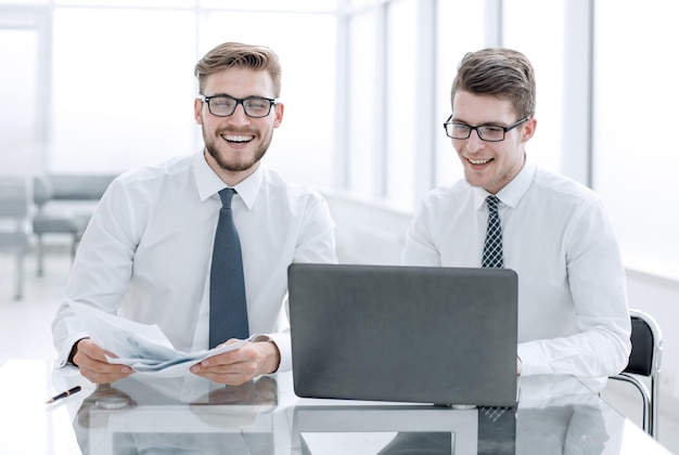 Employés heureux assis à une table dans un nouveau bureau et technologie