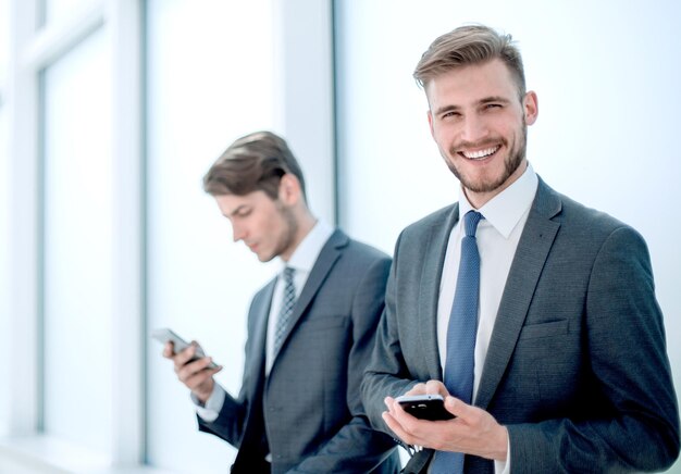 Employés qui réussissent à l'aide de leurs smartphones assis dans le hall du bureau