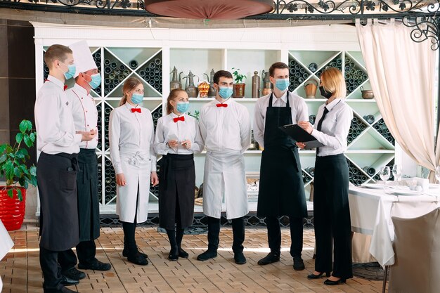 Employés d'un restaurant ou d'un hôtel portant des masques de protection