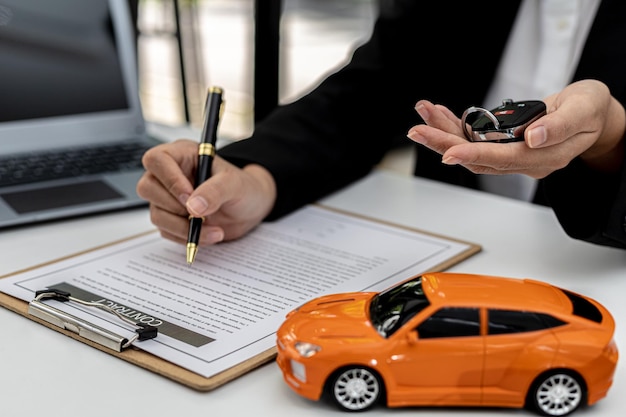 Les employés de la société de location de voitures vérifient le contrat avant d'envoyer la voiture au client pour louer la voiture, préparant le contrat pour que le client signe le contrat de location. Concept de location de voiture.