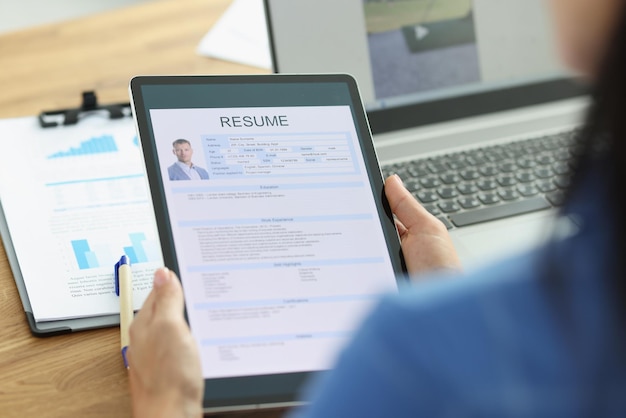 Employeur de femme tenant une tablette numérique dans les mains avec le curriculum vitae de l'homme pour l'emploi à distance en gros plan