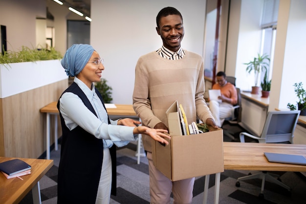 Photo employeur montrant à l'homme son bureau à son nouveau travail tout en portant une boîte d'effets personnels