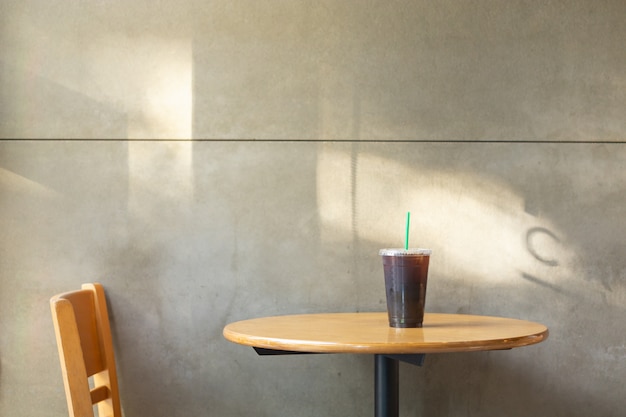 Emporter une tasse en plastique de café noir glacé Americano sur une table en bois dans le restaurant