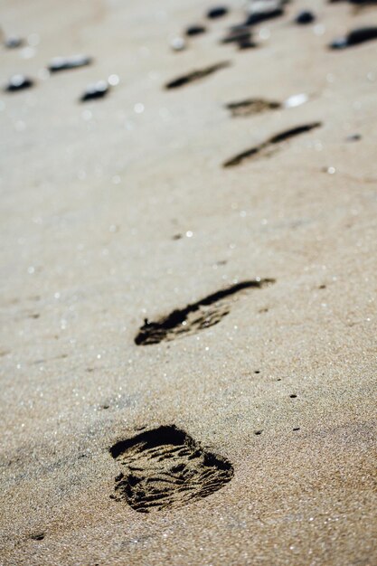 Photo des empreintes de chaussures sur le sable de la plage