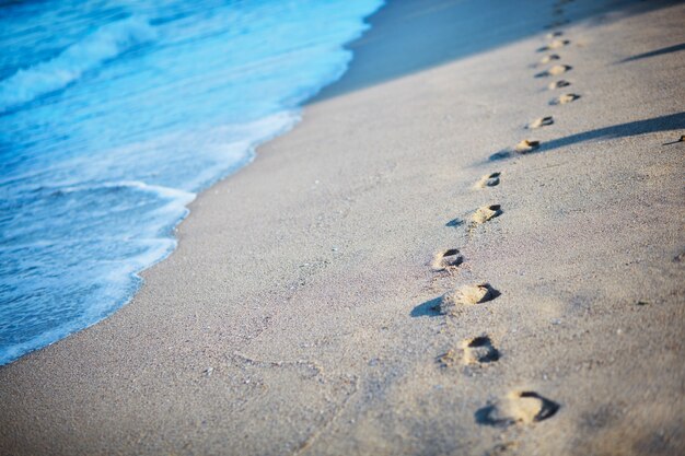 Empreintes de pas dans le sable au bord de la mer