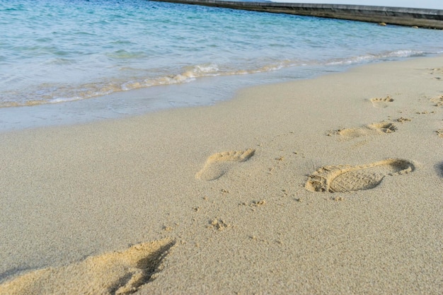 Empreintes de pas dans le sable d'une plage au bord de la mer Méditerranée sur l'île d'Ibiza en Espagne, scène de vacances et d'été