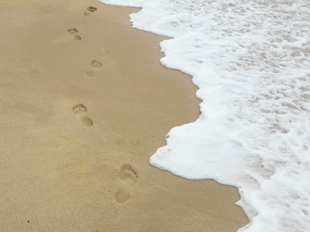 Empreintes de pas dans le sable sur la plage