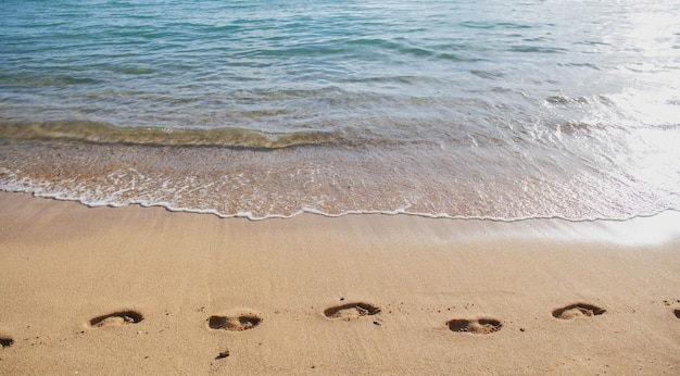 Empreintes de pas de fond de plage dans le concept d'empreinte de pied de sable pour les vacances de voyage