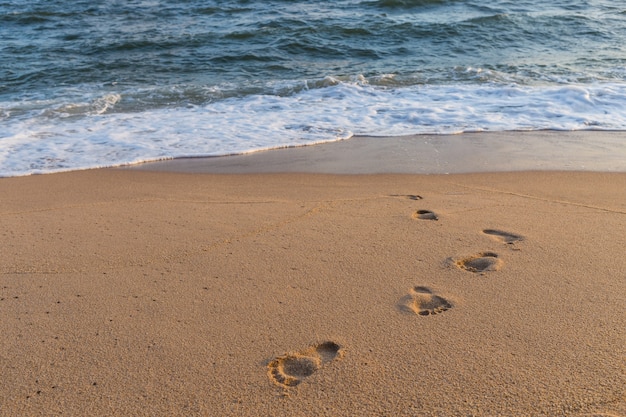 Empreintes de pas sur le fond de la plage de sable