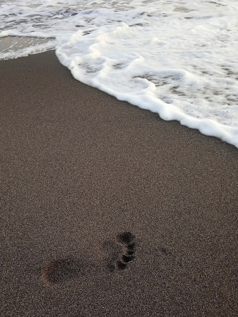 Empreintes de pas sur la plage pendant le coucher du soleil en été