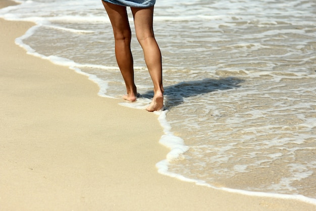 Empreintes de pieds femelles dans le sable sur la plage en été