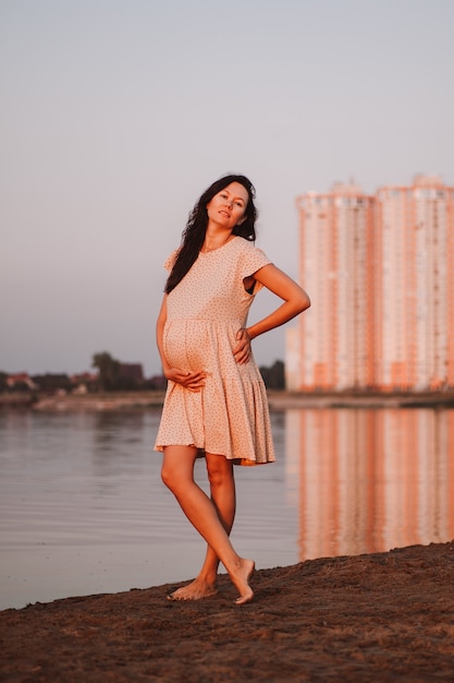 Photo enceinte brune sur fond de ville belle jeune femme asiatique aux longs cheveux bruns se dresse nue...