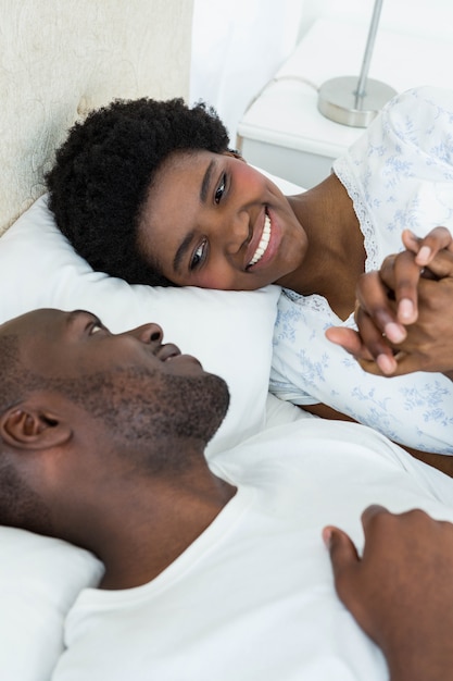 Enceinte couple souriant tout en vous relaxant sur le lit à la maison
