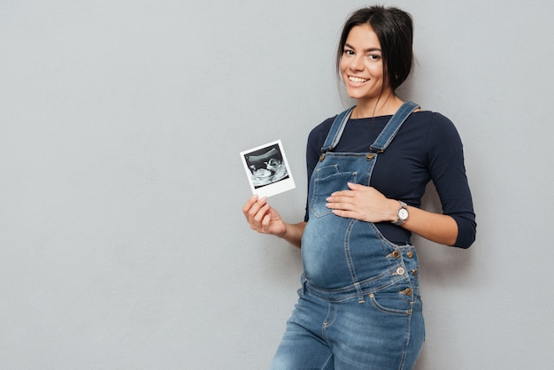 Enceinte femme gaie montrant des échographies