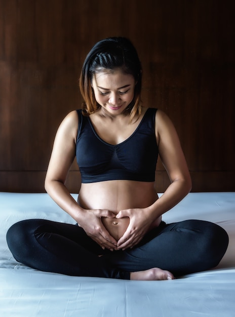 Enceinte femme tenant ses mains sur son ventre gonflé formant un coeur