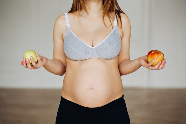 Enceinte de pommes. Deux pommes dans la paume de la femme enceinte.