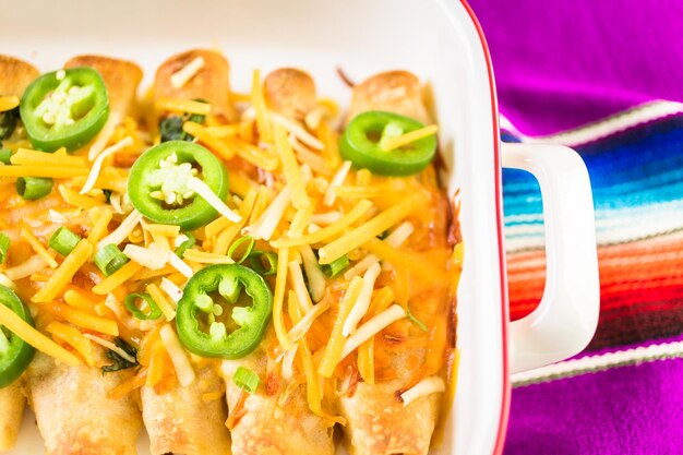 Enchiladas au poulet avec fromage cheddar et sauce.